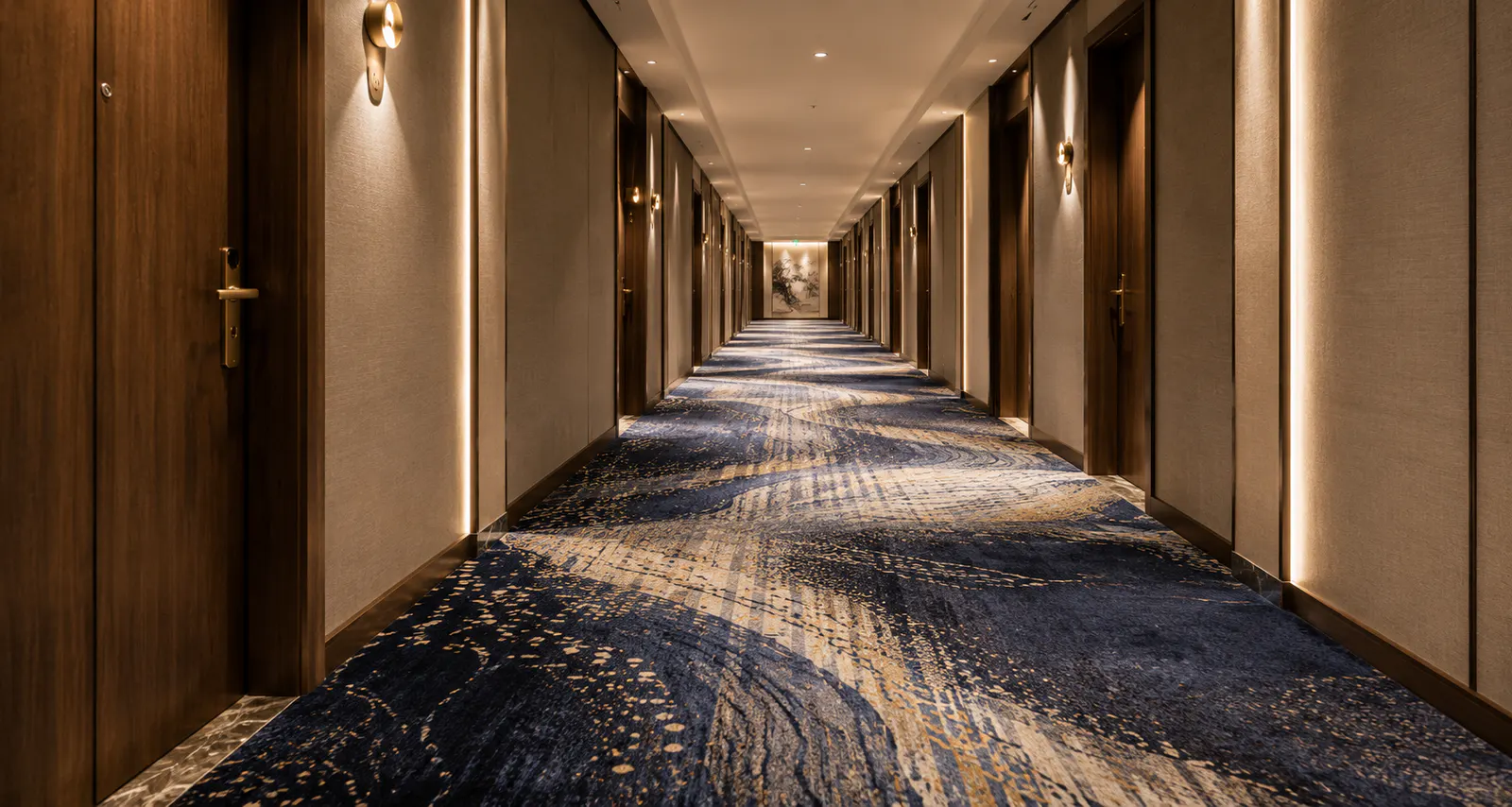Luxury hotel corridor with patterned wall-to-wall carpet and warm hospitality lighting